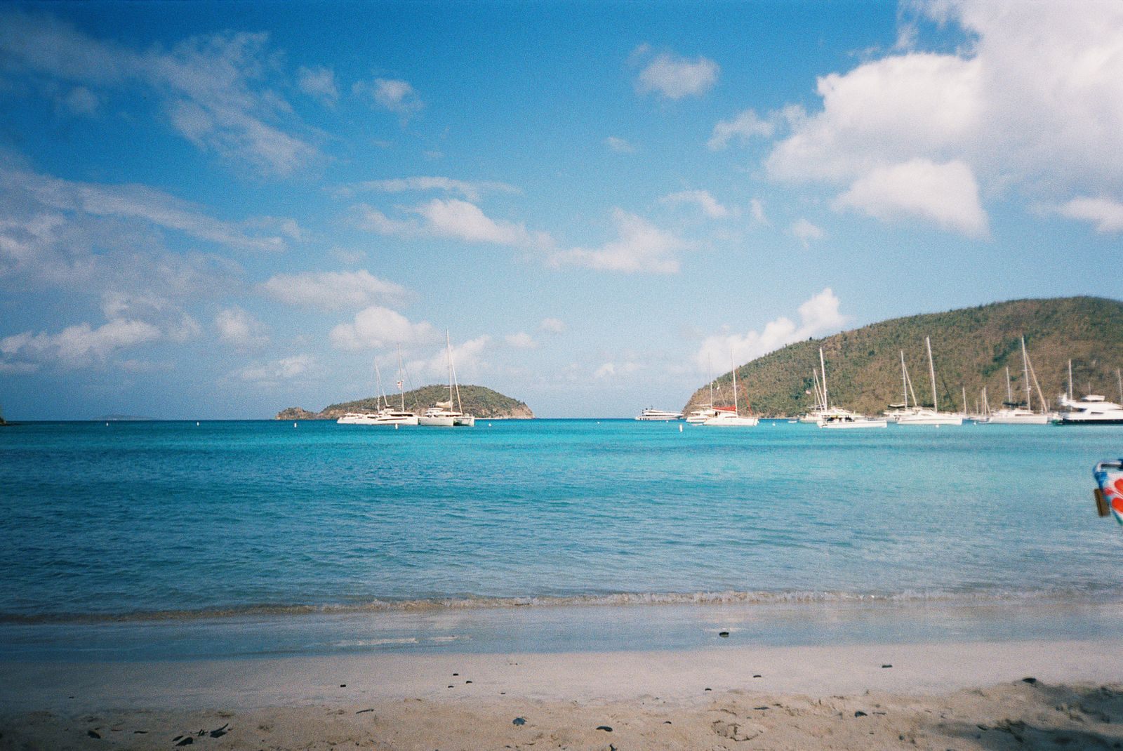 Calm Caribbean beach with sailboats and green islands, an easy setting for the best cruise for first timers