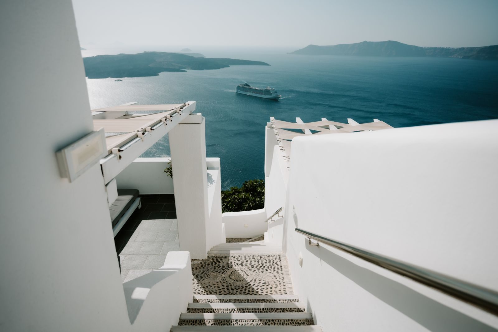 White steps leading down to the Aegean with a cruise ship below, the kind of view recommended cruises are planned around