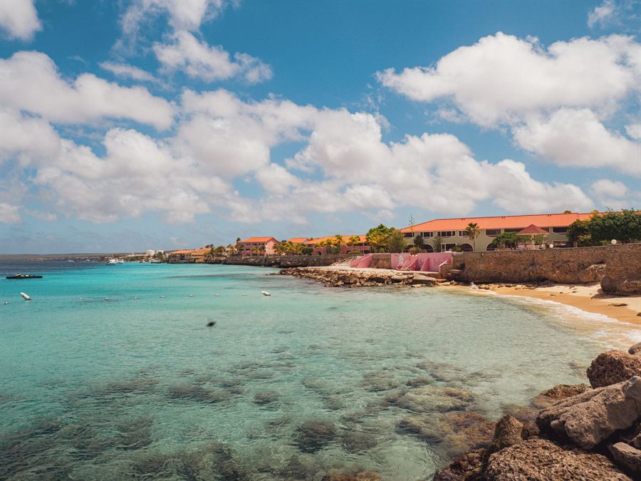Turquoise cove and sandy beach below a colorful waterfront