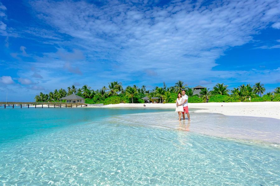 Couple on a white beach with palm trees and turquoise water