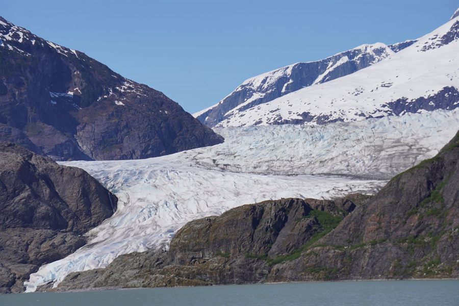Glacier flowing down a valley between snowy peaks