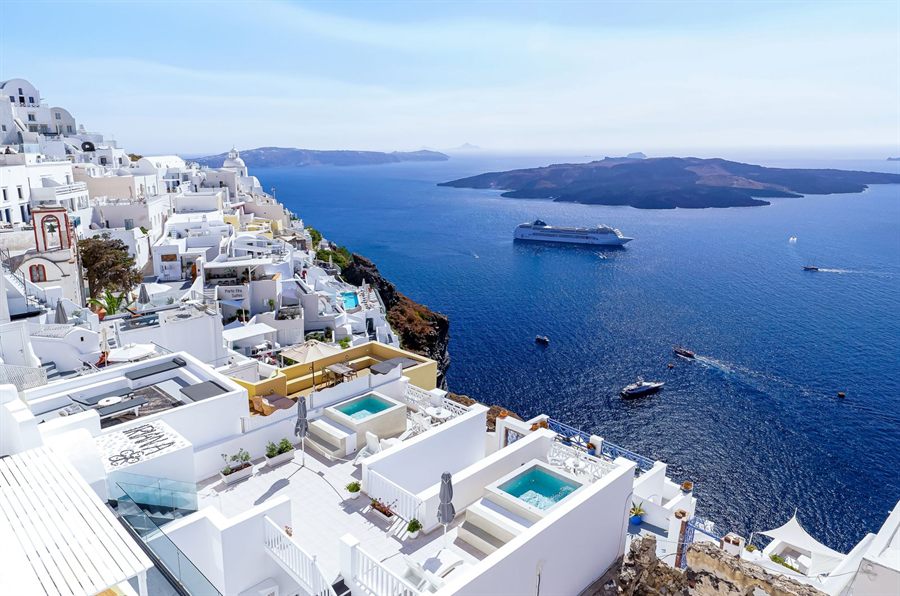 Santorini cliffs and pools above the caldera with a cruise ship at anchor