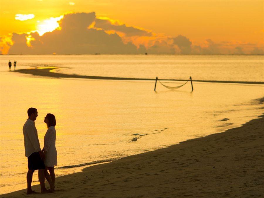Couple standing on a beach at golden sunset