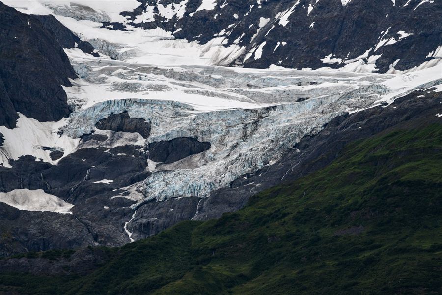 Glacier spilling between dark mountains toward the sea in Alaska